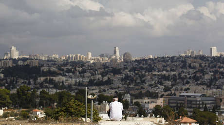 Un hombre sentado con una vista de Jerusalén de fondo en Givat HaMatos, un barrio al sur de Jerusalén.