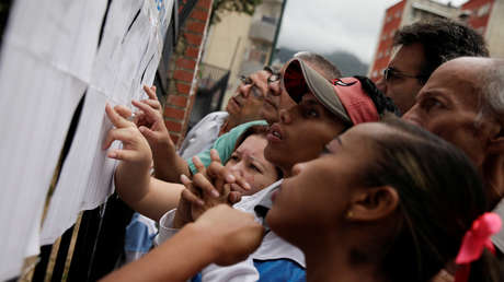 La gente consulta su nombre en una lista en un centro electoral durante las elecciones municipales del 10 diciembre de 2017 en Caracas, Venezuela.