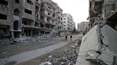 Residentes de Duma pasan junto a edificios destruidos, el 24 de noviembre de 2013.