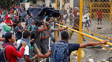Los migrantes centroamericanos empujan la puerta de la frontera mientras intentan internarse en México y seguir con rumbo a EE.UU., en Tecún Uman (Guatemala), 28 de octubre de 2018.