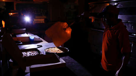 Un hombre cocina a la luz de las velas y linternas en una pizzería en Caracas, el 9 de marzo de 2019.
