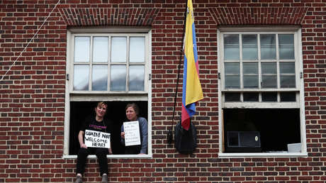 Activistas muestran carteles desde una de las ventanas de la Embajada de Venezuela en Washington, 25 de abril de 2019.