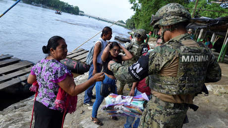 Policía mexicano solicita una identificación a una mujer de Guatemala tras cruzar el Río Suchiate, México, 16 de junio de 2019.