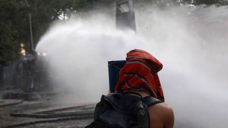 Un manifestante se protege de los cañones de agua disparados por la policía durante una protesta antigubernamental en Satiago de Chile, el 1 de noviembre de 2019.