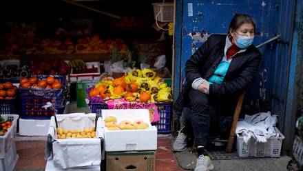 Una mujer se sienta al lado de un puesto de frutas en la ciudad de Wuhan, Hubei, China, el 11 de abril de 2020.