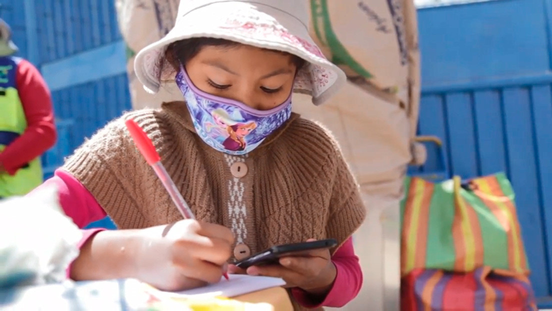 10-year-old Peruvian girl studying by cellphone while helping her aunt at a soft drink stall