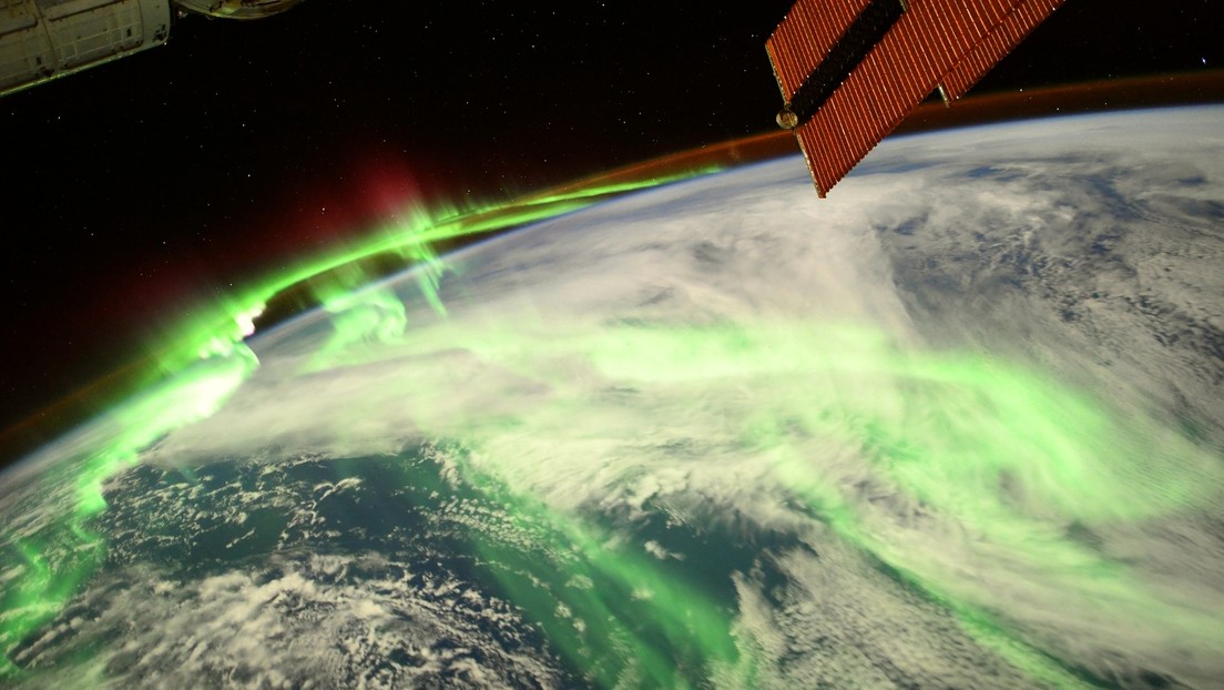 Astronaut shows a dazzling photo taken from space of a green and red aurora shining across the earth