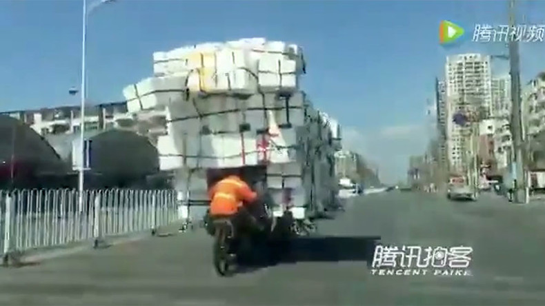 Chinese man defies gravity to transport mountain of boxes on tiny bike (VIDEO)