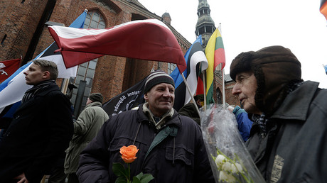 People hold flowers as they wait for an annual procession commemorating the Latvian Waffen-SS (Schutzstaffel) unit, also known as the Legionnaires, in Riga, Latvia, March 16, 2016 © Ints Kalnins
