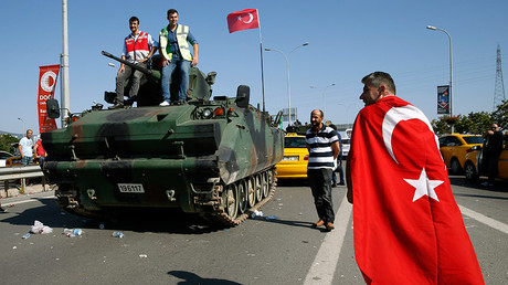 A man wrapped in a Turkish flag walks past a military vehicle in front of Sabiha Airport, in Istanbul, Turkey July 16, 2016 © Baz Ratner