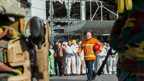 Staff members at Brussels airport and rescuers stand outside the terminal for a ceremony March 23, 2016. © Geert Vanden Wijngaert
