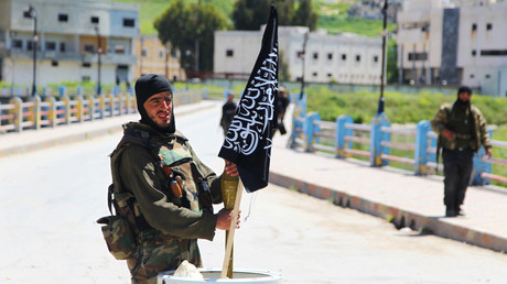 File photo: A Nusra Front fighter carries a shell near a Nusra Front flag on his weapon in Jisr al-Shughour town, after rebels took control of the areaю. © Ammar Abdullah