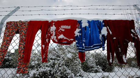 Clothes that belong to stranded refugees are covered with snow as they hang on a fence during a show storm at a refugee camp north of Athens, Greece January 10, 2017. © Yannis Behrakis