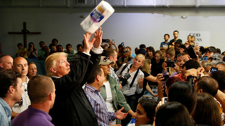 U.S. President Donald Trump tosses rolls of paper towels to people at a hurricane relief distribution center at Calvary Chapel in San Juan, Puerto Rico, October 3, 2017. © Jonathan Ernst