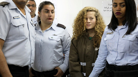 Palestinian teen Ahed Tamimi enters a military courtroom escorted by Israeli Prison Service personnel at Ofer Prison near the West Bank city of Ramallah, December 28, 2017 © Ammar Awad