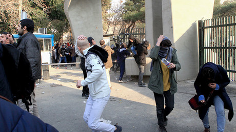 Iranian students run for cover from tear gas at the University of Tehran during a demonstration driven by anger over economic problems, in the capital Tehran on December 30, 2017 © AFP 