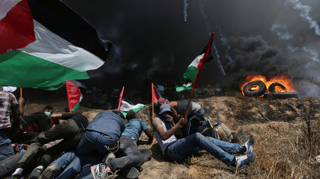 Palestinian demonstrators take cover from Israeli fire and tear gas. © Ibraheem Abu Mustafa / Reuters