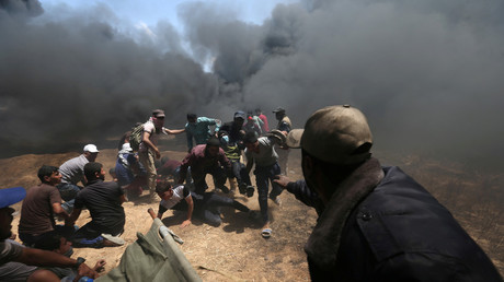 A wounded Palestinian demonstrator is evacuated as others take cover © Ibraheem Abu Mustafa/Reuters