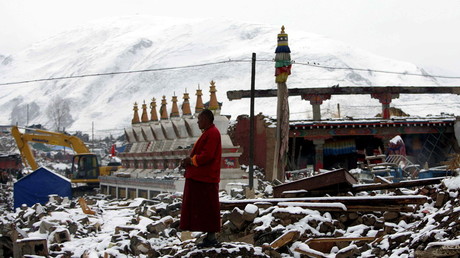 A Tibetan monk stands watch as workers clear the rubble following an earthquake in Qinghai on April 22, 2010.© AFP