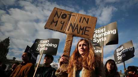 Protesters hold placards during a demo against bombing Syria outside parliament, London, April 16, 2018.  © Hannah Mckay