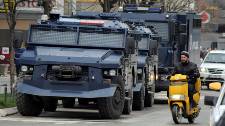 FILE PHOTO: A man rides on a scooter along a street past parked Kosovo police armored vehicles in Kosovo, on March 27, 2018. Â© Laura Hasani
