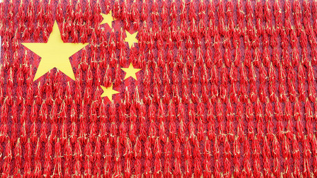 A giant Chinese flag decorated with red chili peppers on the side of a building© China Stringer Network