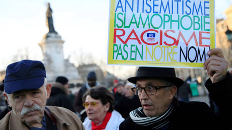 FILE PHOTO. A protester in France hold a sign that reads: "Antisemitism, islamophobia, racism - not in our name". ©REUTERS / Gonzalo Fuentes