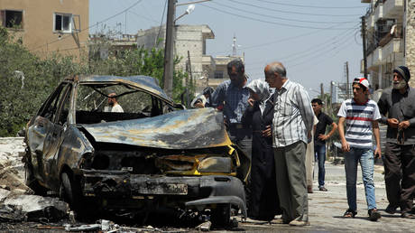 Civilians inspect a burnt car at a site hit by an airstrike in the rebel-controlled city of Idlib, Syria June 29, 2016. © REUTERS/Ammar Abdullah