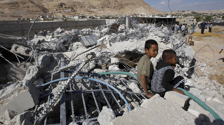Palestinian boys sit in the rubble of structures demolished by Israel's Civil Administration, FILE PHOTO: © Reuters / Mohamad Torokman