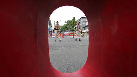 Indian security personnel stands guard behind a roadblock along a deserted street during restrictions in Jammu, August 5, 2019. © REUTERS/Mukesh Gupta