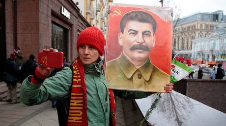 A demonstrator takes a selfie with a portrait of Josef Stalin. © Reuters / Andrey Volkov