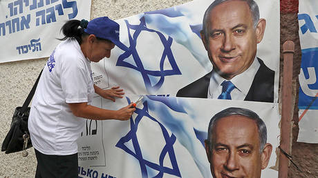 A woman places electoral banners for the Likud party showing chairman and Israeli Prime Minister Benjamin Netanyahu in the southern Israeli city of Beersheva on September 15, 2019.