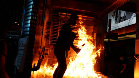 An anti-government protester sets fire outside Mong Kok Mass Transit Railway (MTR) station during a protest, in Hong Kong, China, October 20, 2019. © REUTERS/Tyrone Siu