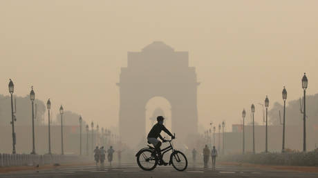FILE PHOTO: A man rides a bicycle on a smoggy morning near India Gate in New Delhi, India.