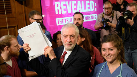 Labour Party leader Jeremy Corbyn holds up documents as he poses for a picture with NHS staff © Reuters / Toby Melville