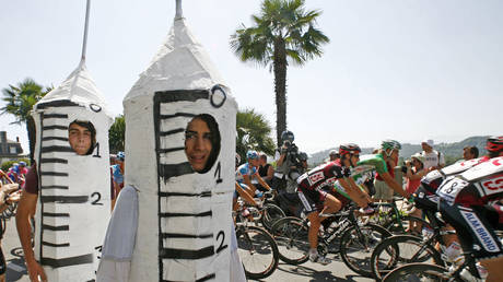 FILE PHOTO: A pack of Tour de France riders cycle past spectators dressed as syringes