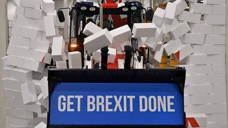 Britain's PM and Conservative leader Boris Johnson drives a Union flag-themed JCB, with the words "Get Brexit Done" inside the digger bucket, through a fake wall emblazoned with the word "GRIDLOCK"