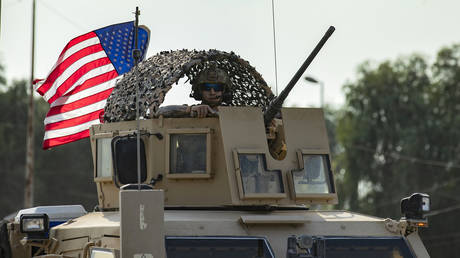 A US soldier stands in an armoured personnel carrier as the US forces pull out of their base in the Northern Syrian town of Tal Tamr, on October 20, 2019