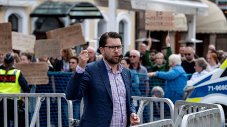 FILE PHOTO: Sweden Democrats leader Jimmie Akesson speaks in Malmo, as protesters hold placards in the background, 2018 © Reuters / Johan Nilsson