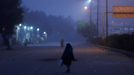 A woman wrapped in a shawl walks on the road during a cold winter evening in New Delhi, India © REUTERS/Adnan Abidi