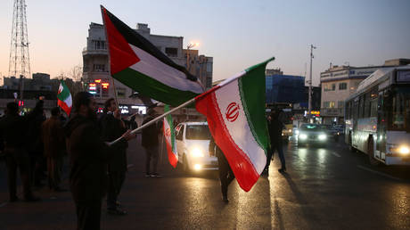 People hold a Palestinian and Iranian flags as they celebrate in the street after Iran launched missiles at U.S.-led forces in Iraq, in Tehran, Iran January 8, 2020.