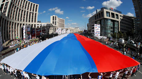 FILE PHOTO: People hold a giant banner during the National Flag Day celebration in Moscow © REUTERS/Maxim Shemetov