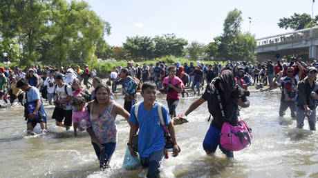 US-bound migrants cross into Mexico through river, hurl stones at military as soldiers block road (WATCH LIVE)