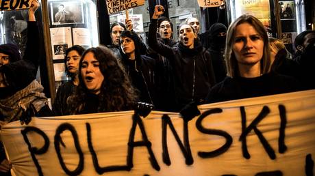 FILE FOTO: Demonstrators hold banners during a protest against French-Polish film director Roman Polanski outside the "Champo" cinema hall in Paris on November 12, 2019