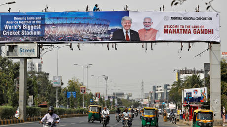 FILE PHOTO: A worker installs a banner with the images of US President Donald Trump and India's Prime Minister Narendra Modi in Ahmedabad, India, ahead of Trump's first state visit.