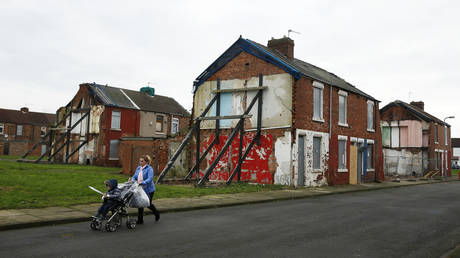 A woman pushes a pram along a semi-derelict terraced street in the Gresham area of Middlesbrough, north-east England © Reuters / Phil Noble