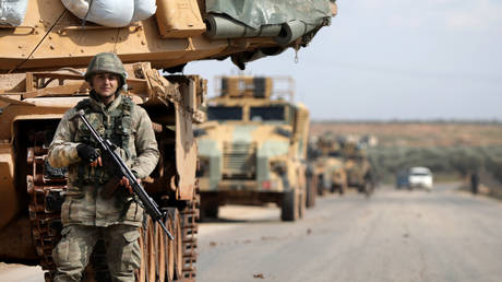 A Turkish soldier stands in front of a military vehicles convoy east of Idlib city in northwestern Syria on February 20, 2020