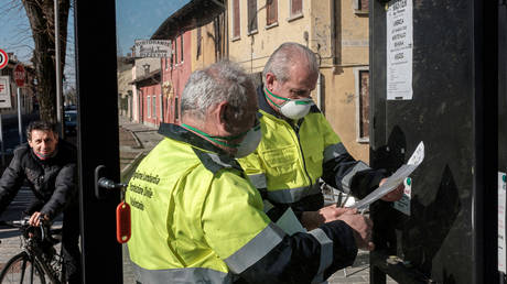 Civil protection officers wearing protective masks put up posters in San Fiorano, Italy © Reuters / Marzio Toniolo