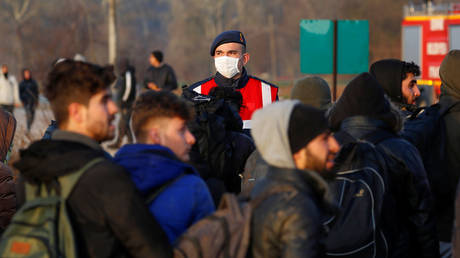 FILE PHOTO: A Turkish gendarmerie officer wearing a face mask is seen as migrants walk next to the Turkey's Pazarkule border crossing with Greece's Kastanies © REUTERS/Leonhard Foeger