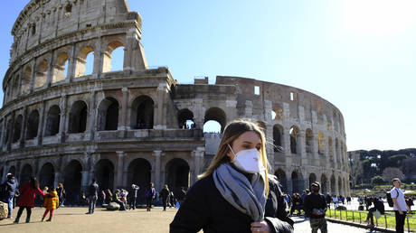 Tourist wearing a protective respiratory mask tours outside the Colosseo monument in downtown Rome, Italy